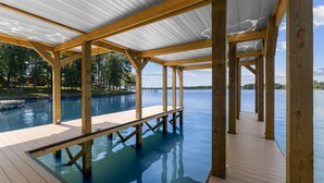 A wooden deck with a pool, surrounded by trees and a clear view of the water. - Lakefront Living W/optional Boat Rental (Mooresville)