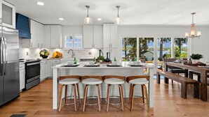A modern kitchen with white cabinets, a stainless steel refrigerator, and a wooden island with bar stools. - Lakefront Living W/optional Boat Rental (Mooresville)