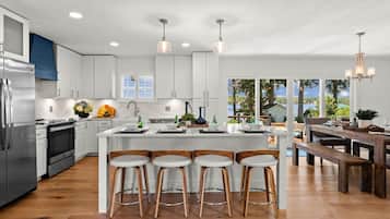 A modern kitchen with white cabinets, a stainless steel refrigerator, and a wooden island with bar stools.