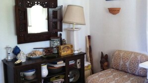 A living room with a sofa, a cabinet with dishes, a lamp, and a mirror. - The magical though (Puglia)