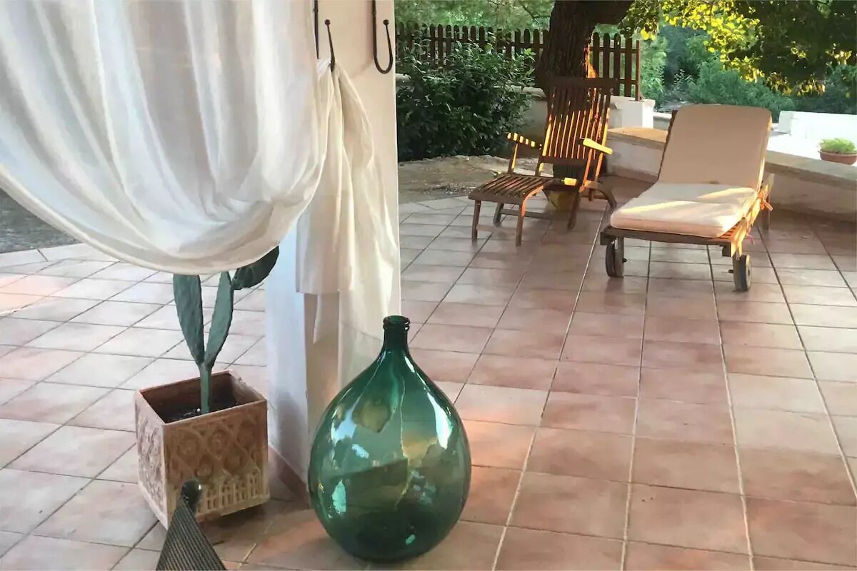 A patio area with a green vase, a chair, and a table.