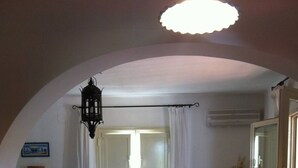 A living room with a white desk, two chairs, a patterned sofa, a decorative rug, and a hanging lantern. - The magical though (Puglia)