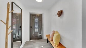 Un pasillo con un banco de madera, un espejo y una puerta con panel de vidrio esmerilado.