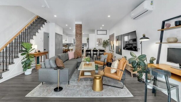 Una sala de estar moderna con una escalera, un comedor y una cocina al fondo.