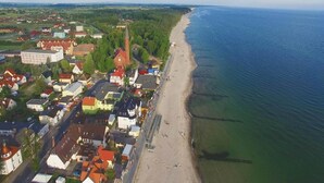 An aerial view of a coastal town with a beach, houses, and a church. - Holiday House in Sarbinowo near Baltic Beach (Sarbinowo)