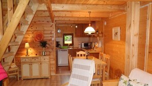 A cozy log cabin interior with a dining area, kitchen, and a staircase. - Holiday House in Sarbinowo near Baltic Beach (Sarbinowo)