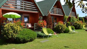 A row of wooden cabins with a well-maintained lawn and outdoor seating area. - Holiday House in Sarbinowo near Baltic Beach (Sarbinowo)