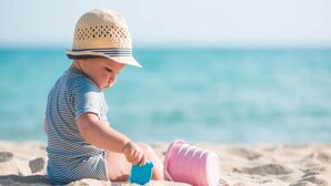 Ein Kind spielt mit Sandspielzeug am Strand.