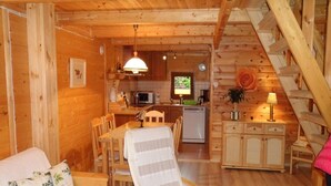 Ein gemütliches Holzblockhaus-Interieur mit Essbereich, Küche und einer Treppe.