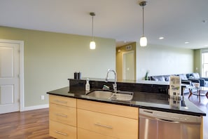 Enjoy cooking in this well-lit kitchen with a sleek countertop, stainless steel dishwasher, and spacious sink area.