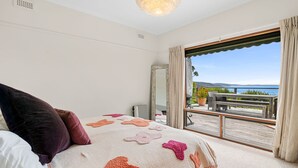 Een slaapkamer met een groot bed, uitzicht op de omgeving en een balkon met tuinmeubilair.