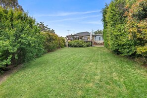A well-maintained lawn with a house in the background. - Sunrise - Tranquility of beachfront living (Lorne)
