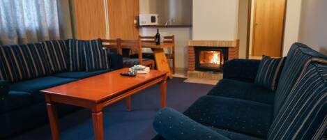 Una sala de estar con sofá, una mesa de centro de madera y una chimenea.