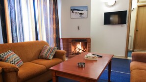 Una sala de estar con un sofá, una mesa de centro, una chimenea y un televisor montado en la pared.