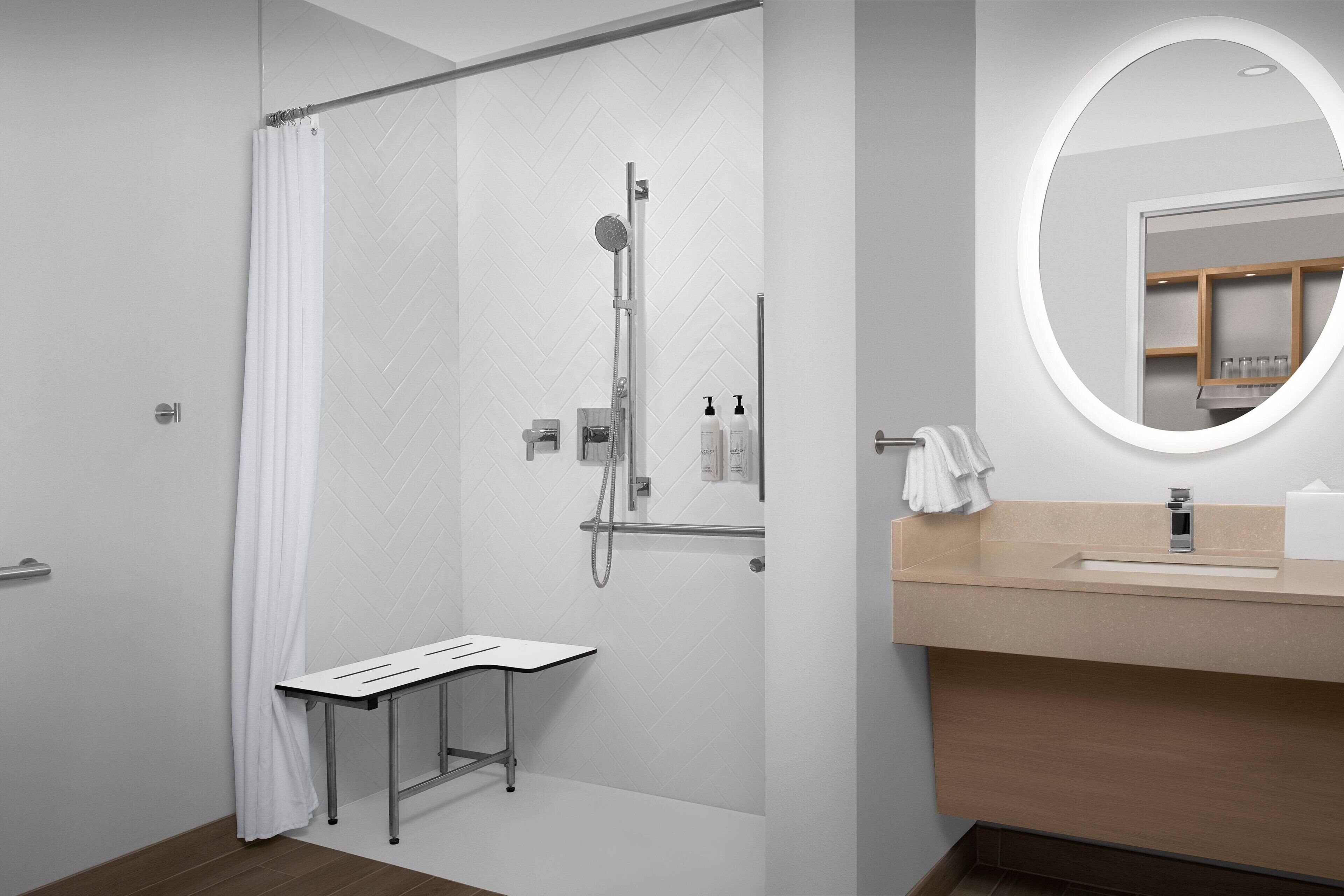 A modern bathroom with a shower, a vanity with a mirror, and a small table.