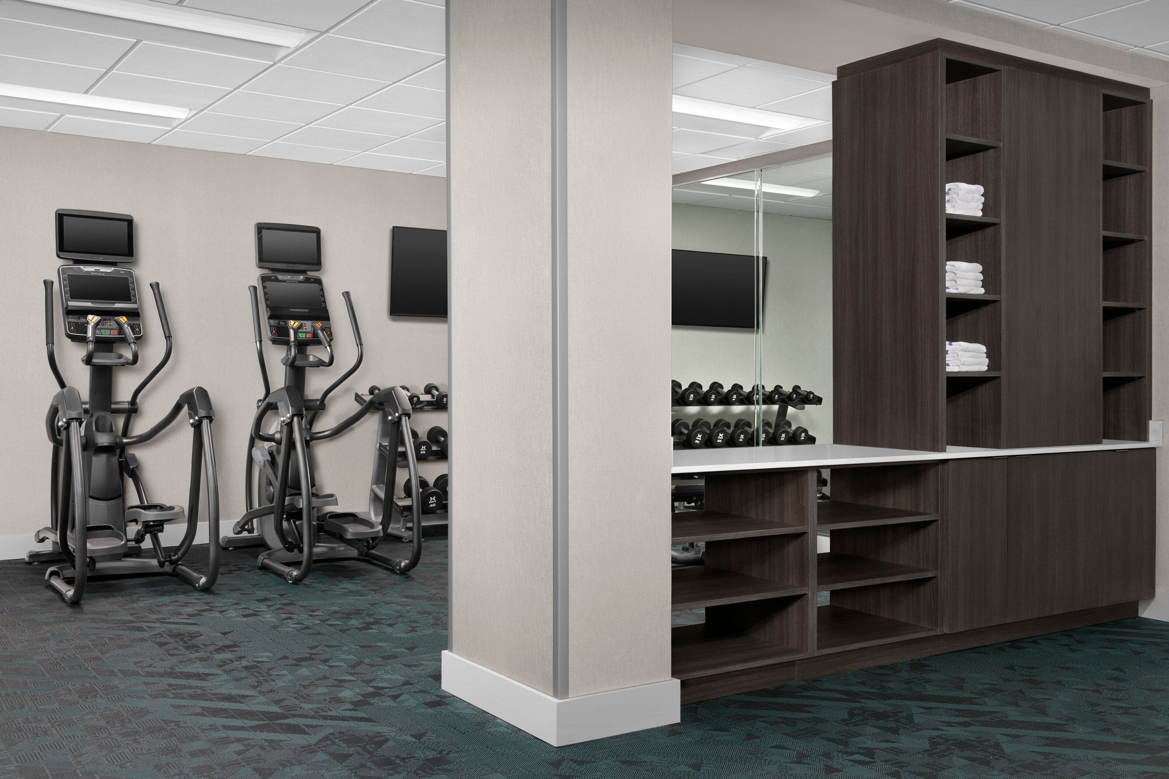 A fitness center with treadmills, elliptical machines, and a weight rack.