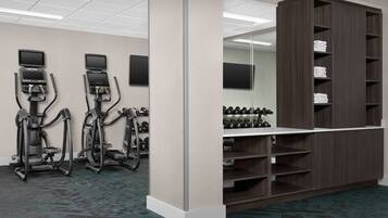 A fitness center with treadmills, elliptical machines, and a weight rack.