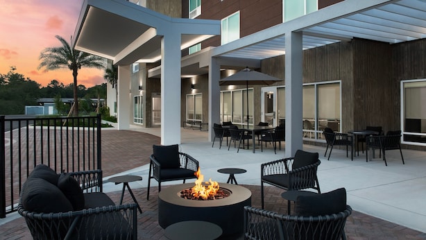An outdoor patio area with wicker chairs, a round table, and a fire pit. - TownePlace Suites Jacksonville Airport (Jacksonville)