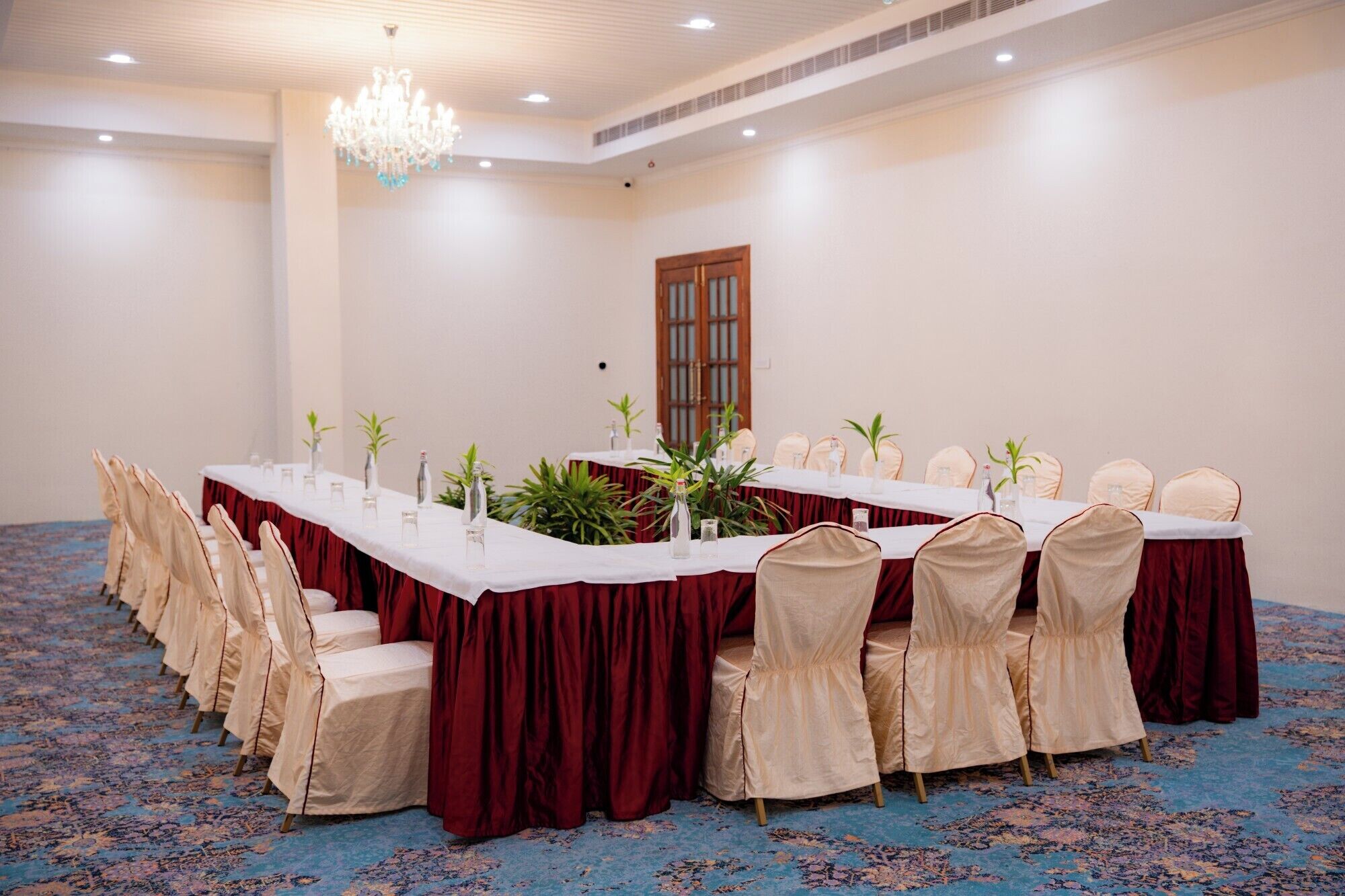 Un salón de conferencias con una larga mesa, sillas y una lámpara de araña.