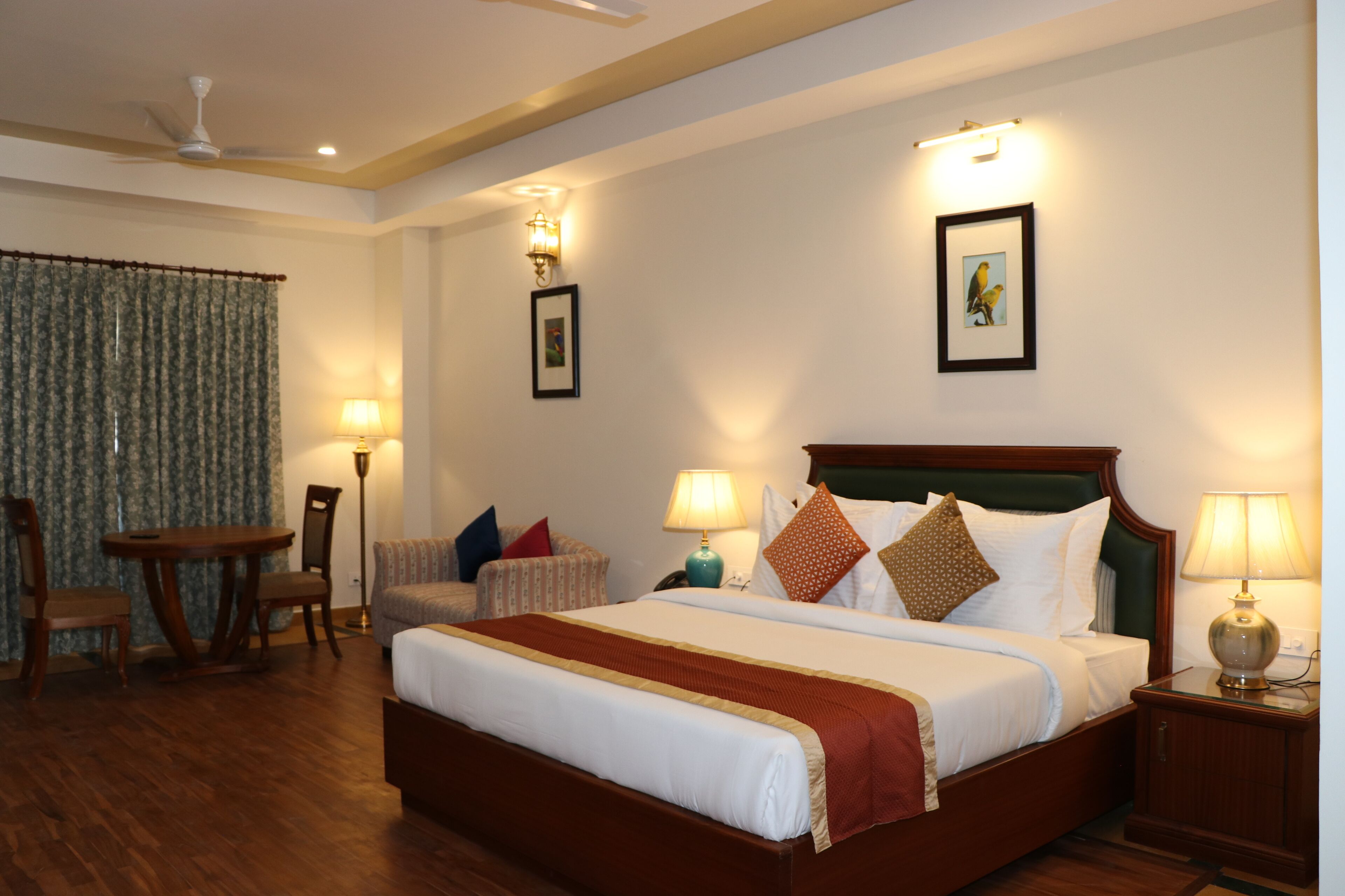 A hotel room with a large bed, a desk, and a chair. There are two lamps on the nightstands.