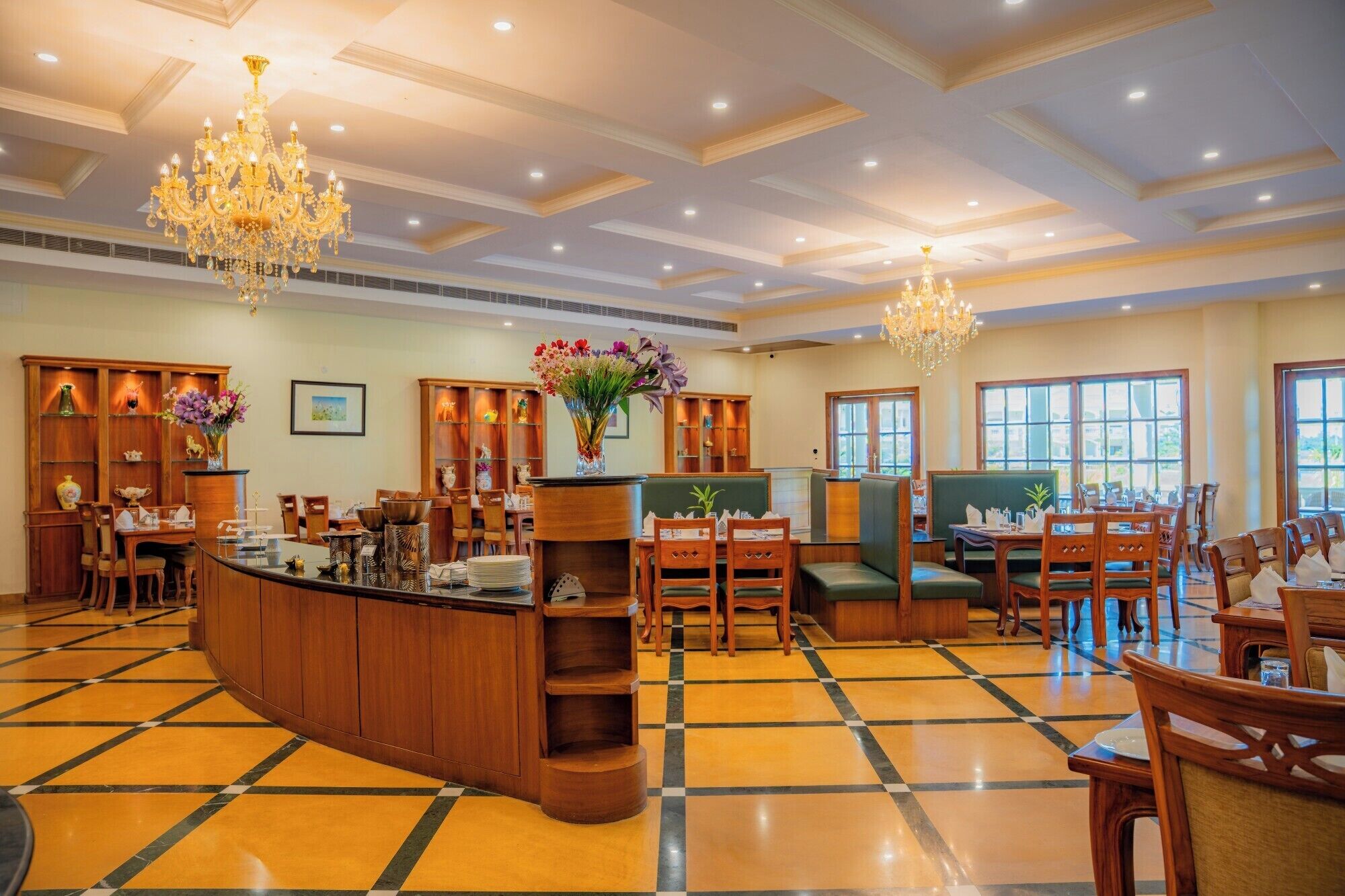 A spacious hotel lobby with a central bar, multiple seating areas, and large windows providing natural light.