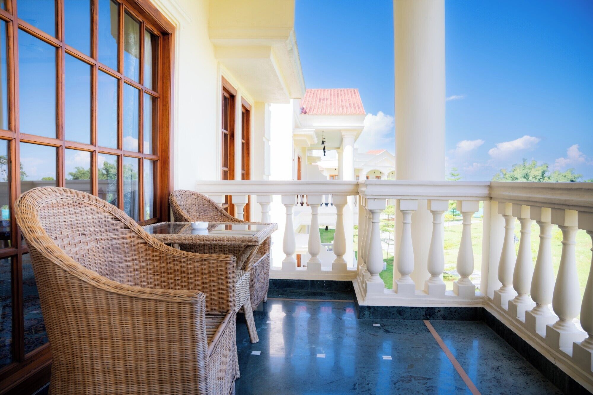 A balcony with wicker furniture and a view of the sky.