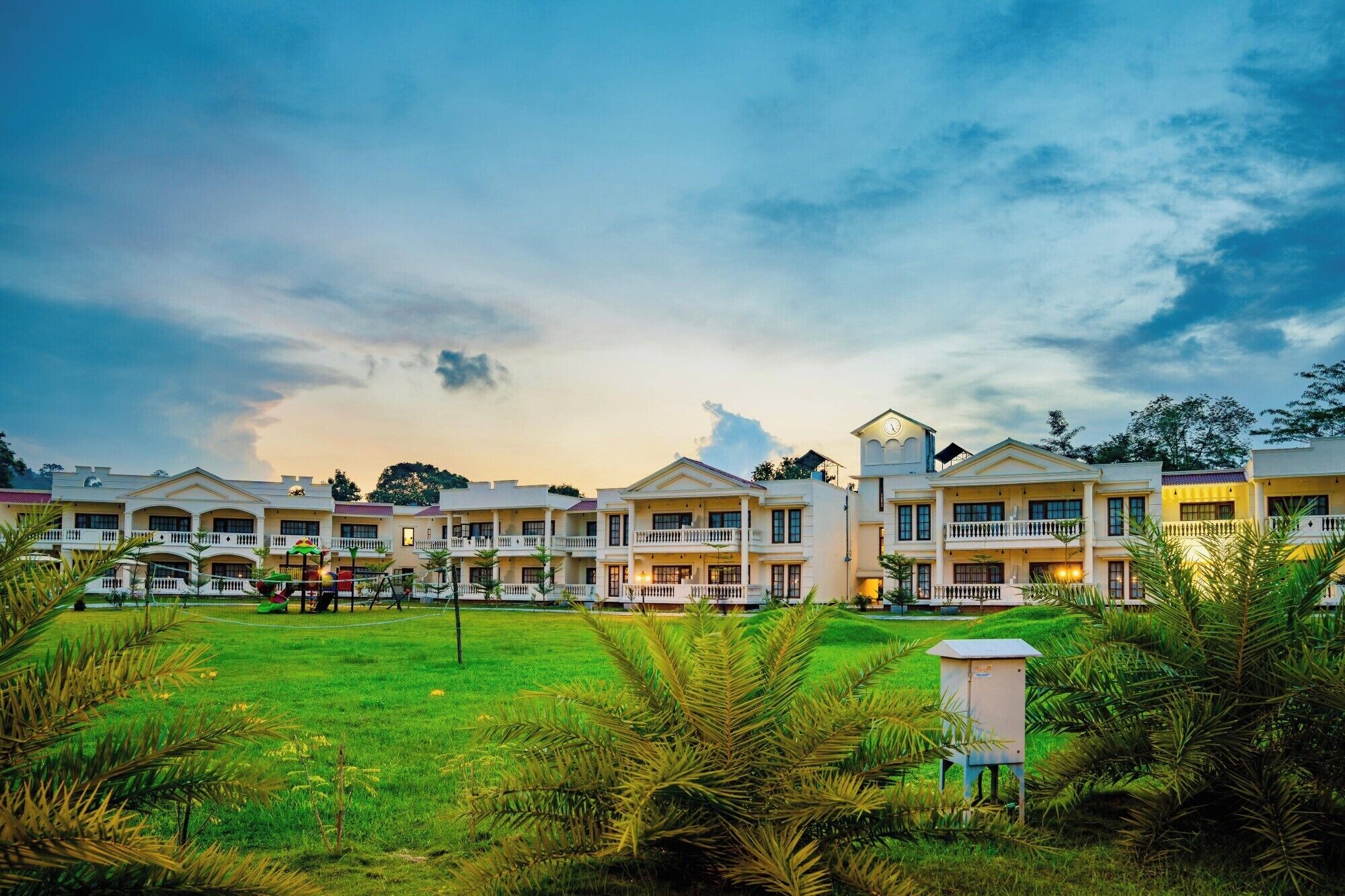 A hotel with multiple-story buildings, a well-maintained lawn, and a clear sky.