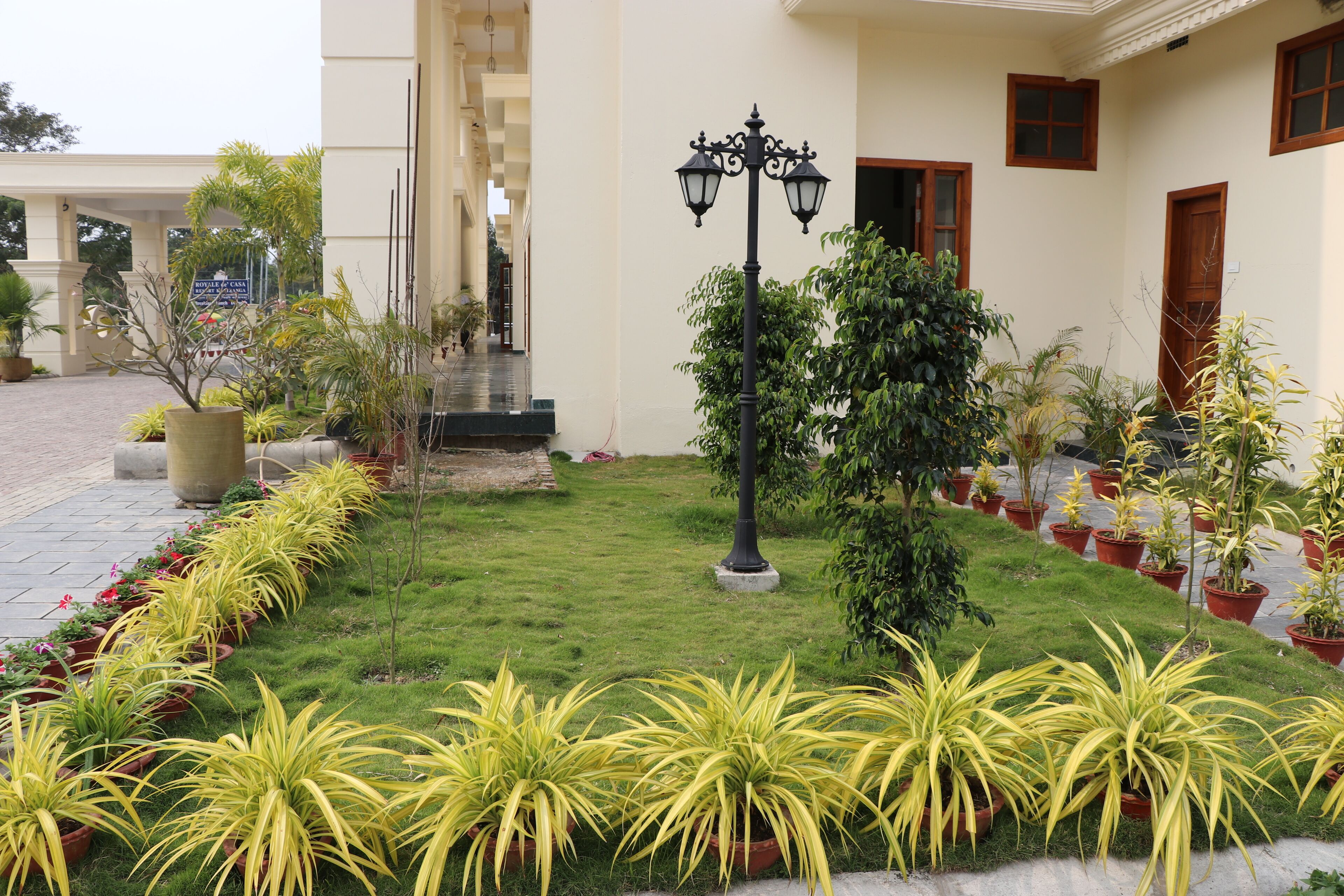A well-maintained garden with potted plants and a central lamp post.