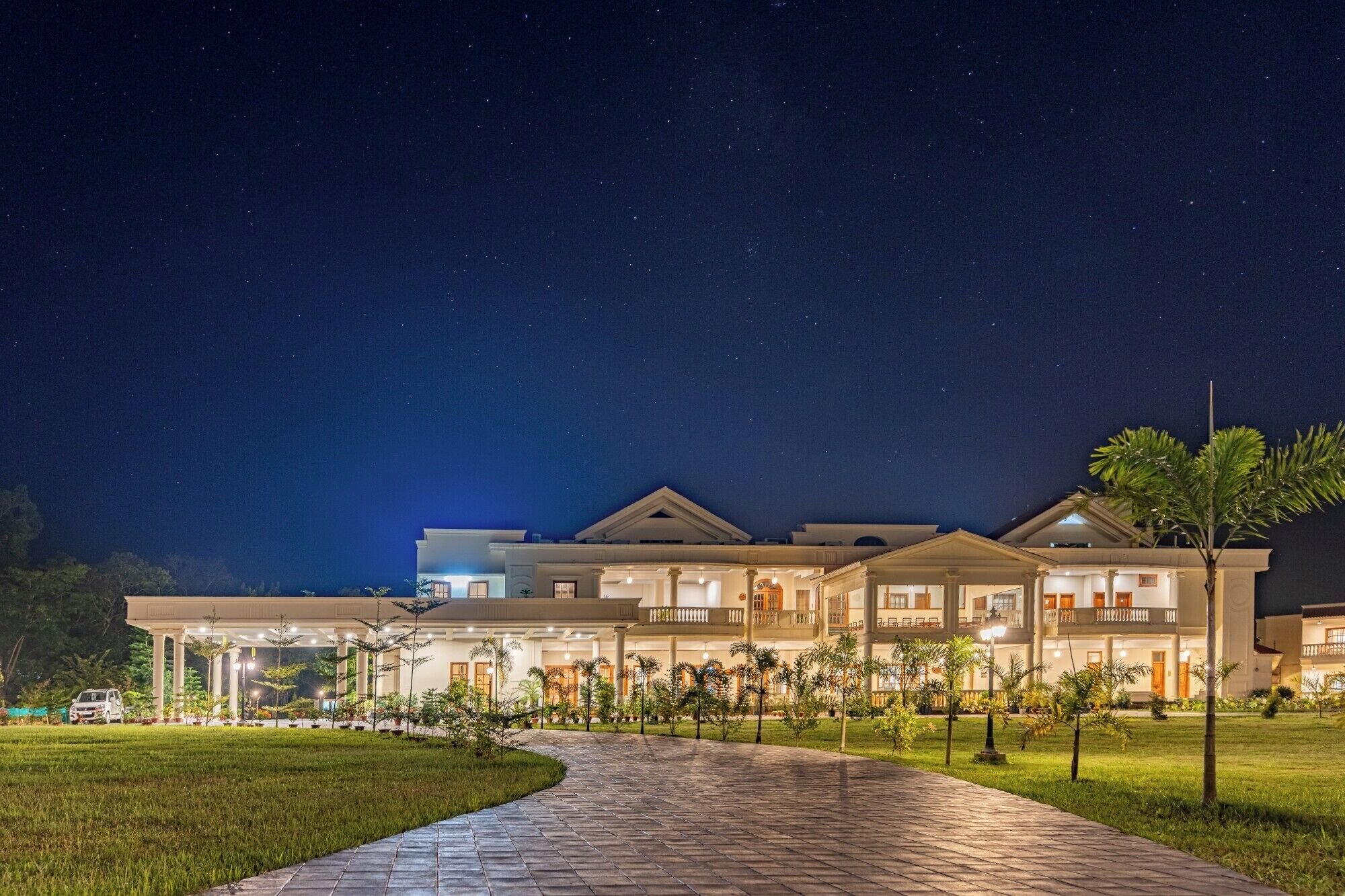 A large, multi-story hotel with a covered outdoor area, a paved walkway, and a well-maintained lawn.