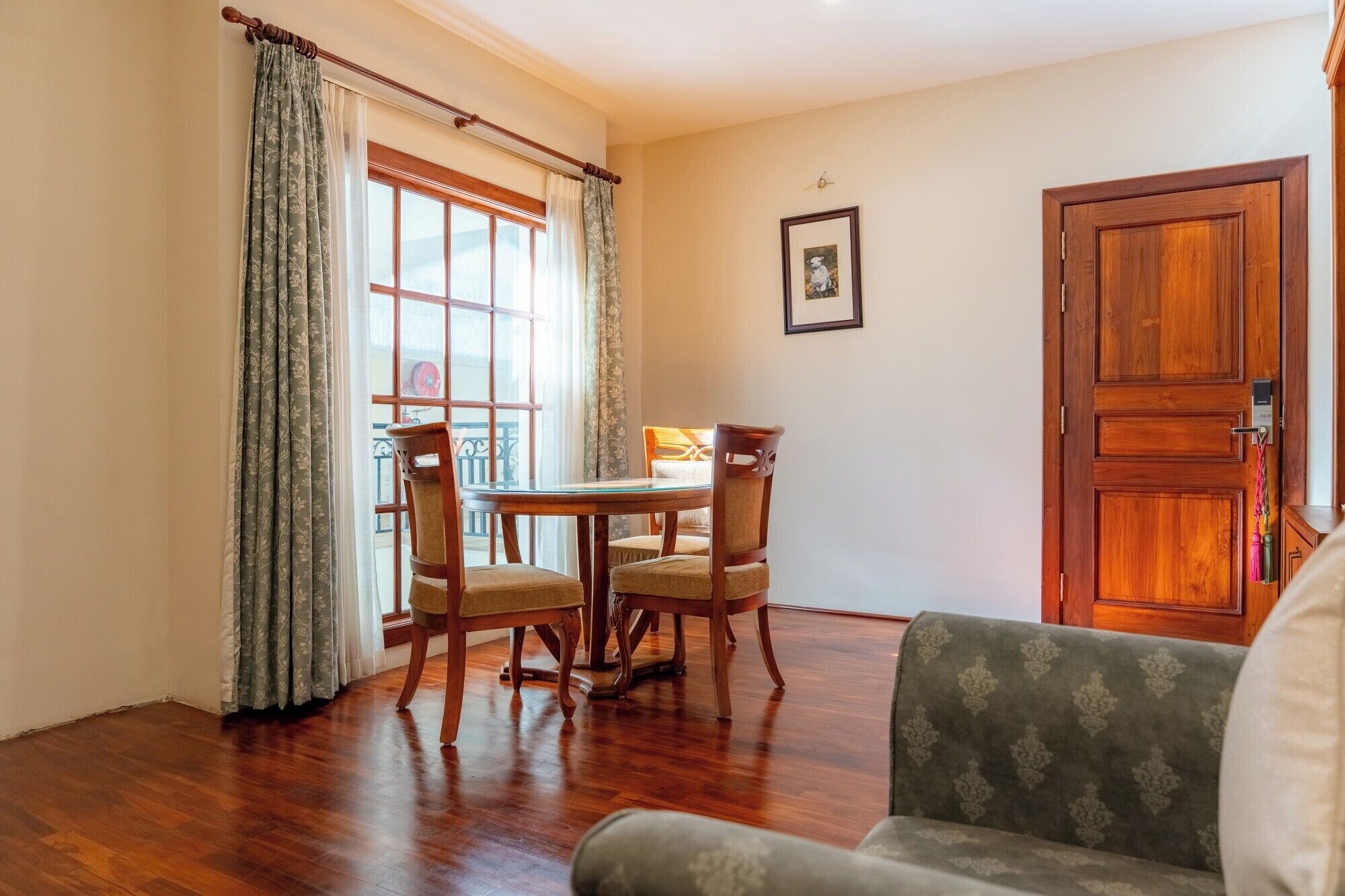 A dining area with a wooden table and chairs, a sofa, and a wooden door.