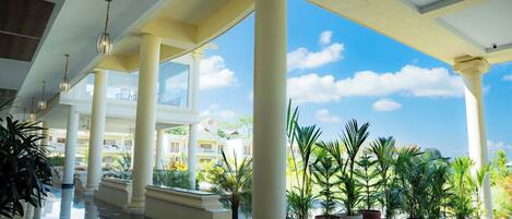 A spacious indoor area with white columns, a polished floor, and potted plants.