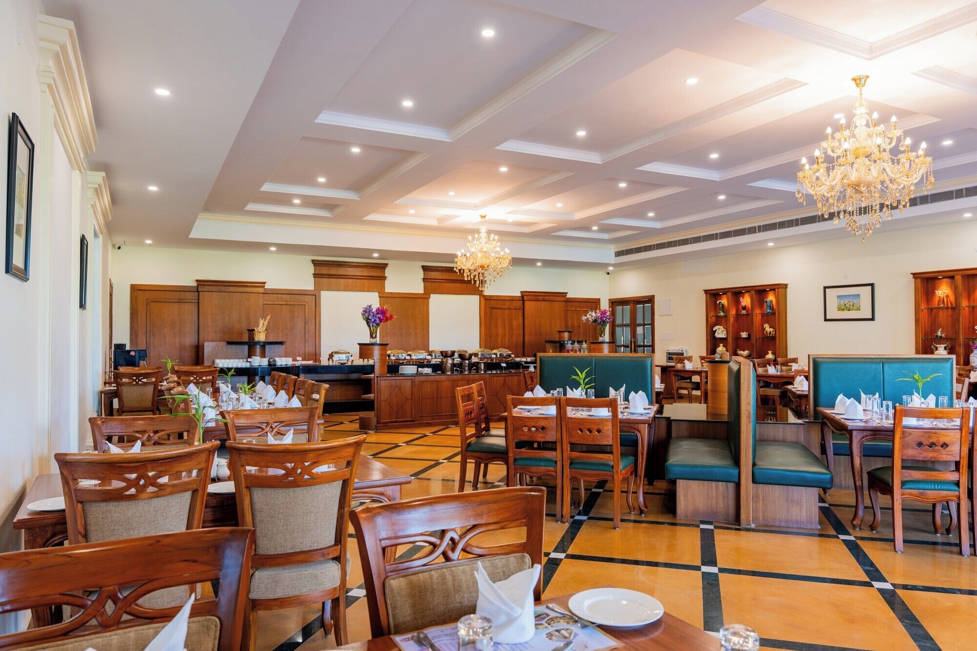 A hotel dining area with wooden furniture, a central bar, and a chandelier.