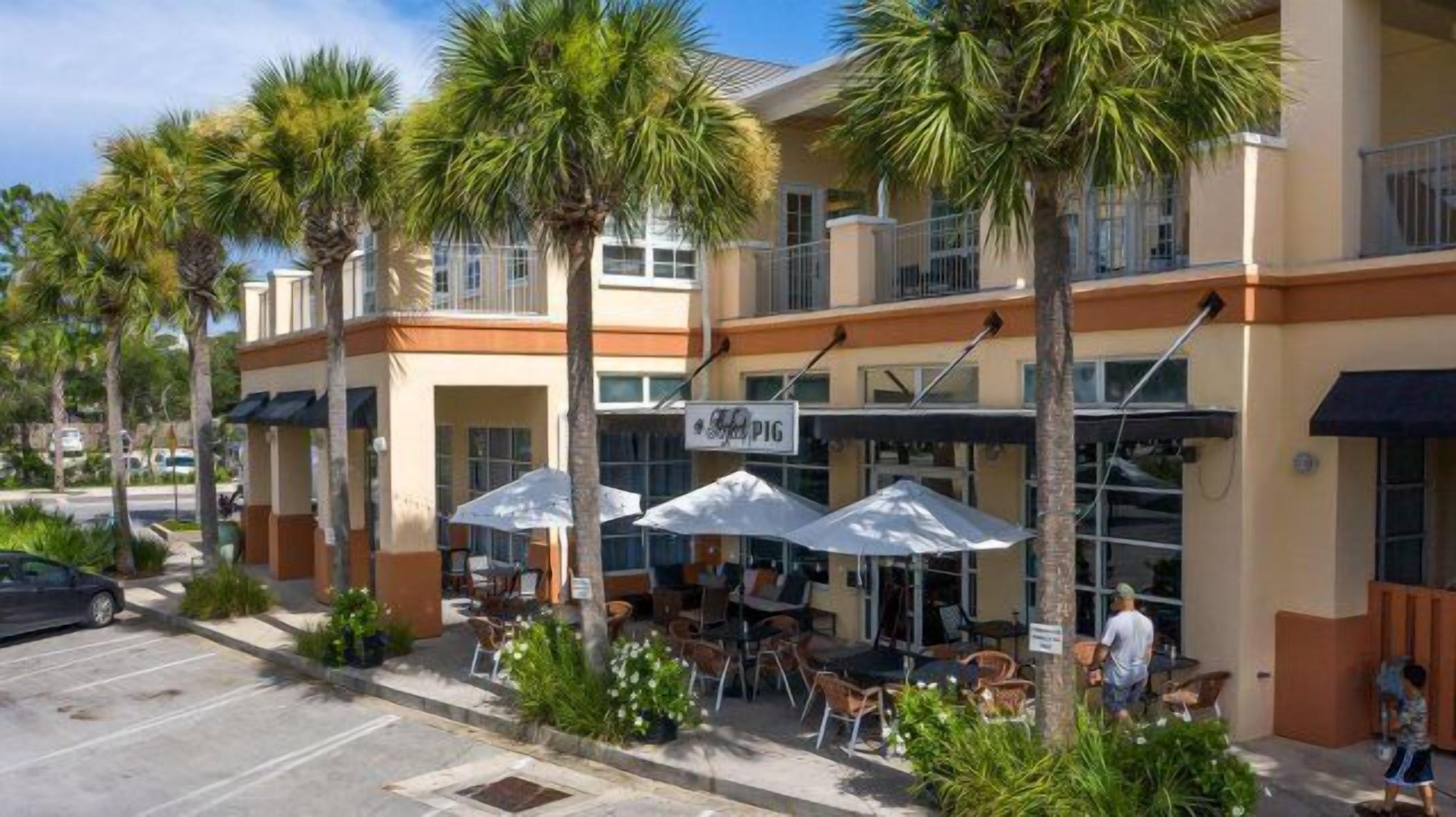 A building with outdoor seating and palm trees.