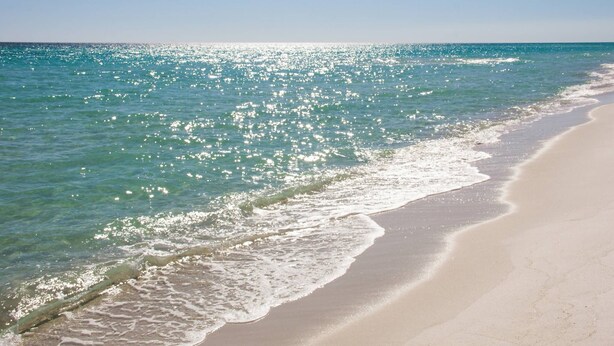 Una playa con agua turquesa cristalina y una orilla arenosa.