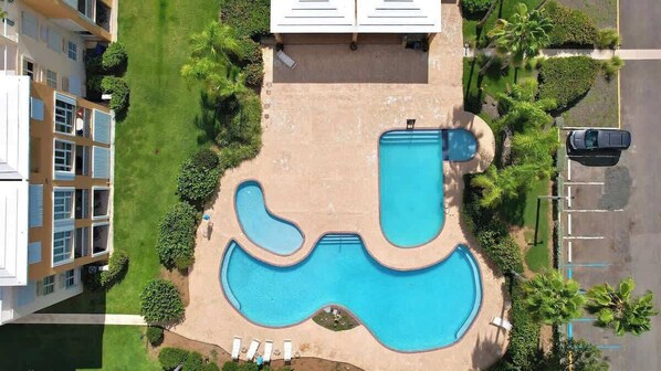 Vista aerea di una zona residenziale con piscina, edifici adiacenti e parcheggio.