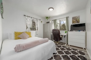 Une chambre à coucher comprenant un lit, un bureau, une chaise, un téléviseur et une armoire.