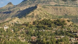 A hillside village with traditional houses and a prominent building in the foreground. - Birhanu Home stay (Lalibela)