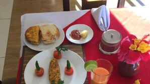 A breakfast table with toast, scrambled eggs, tomatoes, a glass of orange juice, and a cup of coffee. - Birhanu Home stay (Lalibela)