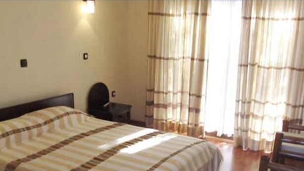 A hotel room with a bed, a desk, and curtains. - Birhanu Home stay (Lalibela)