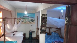 Una habitación con una cama, una mesita pequeña, un estante en la pared y un cuadro de un paisaje montañoso.