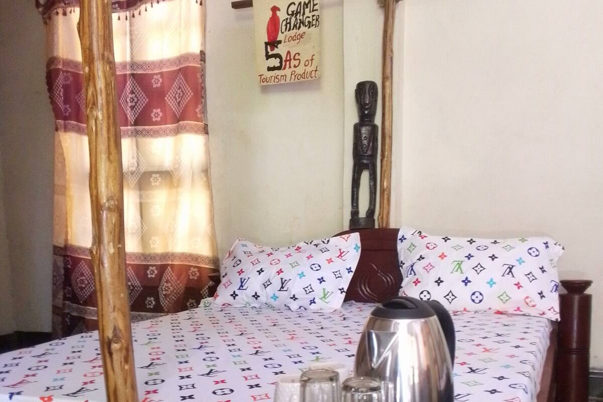 A room with a bed, a table with a kettle, salt and pepper shakers, and a sign on the wall.
