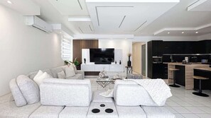 Ein modernes Wohnzimmer mit Sofa, Couchtisch und Fernseher.