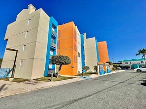 A modern building with a flat roof, multiple balconies, and a clear sky.