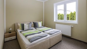 A bedroom with a bed, bedside table, and a window with a view of trees. - Amselresidenz 4 - STAR (Binz)