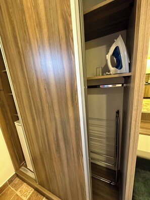 A wooden wardrobe with a metal shelf, a white appliance, and a blue object on the shelf.