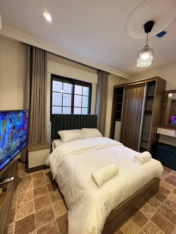 A hotel room with a bed, a television, a wardrobe, and a window.