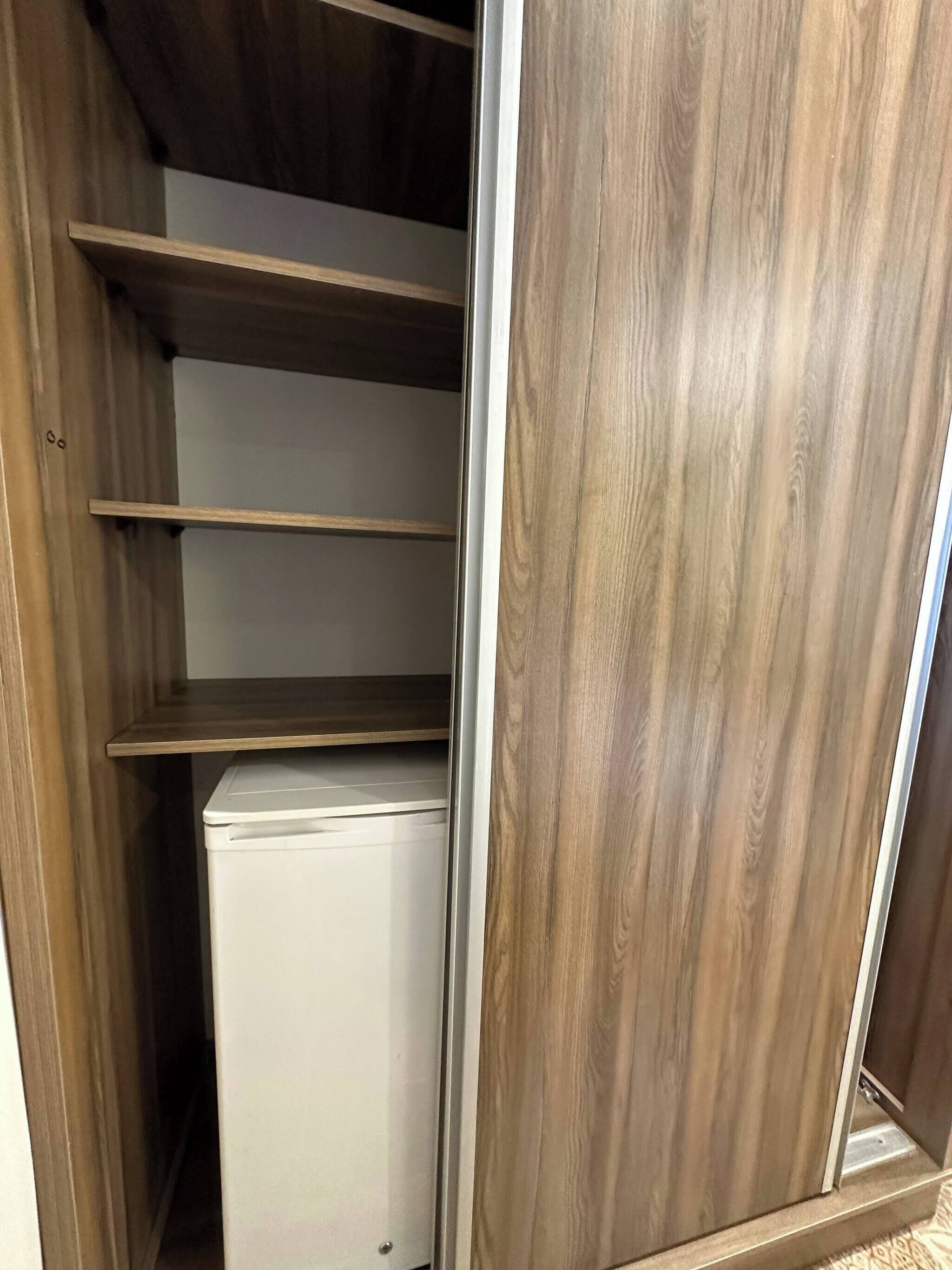 Ein begehbarer Kleiderschrank mit Holzböden und einem weißen Gerät.