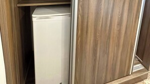 Un dressing avec des étagères en bois et un appareil électroménager blanc.