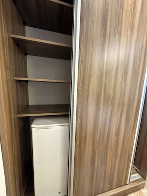 A walk-in closet with wooden shelves and a white appliance.