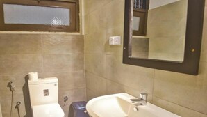 Een badkamer met toilet, wastafel en spiegel.